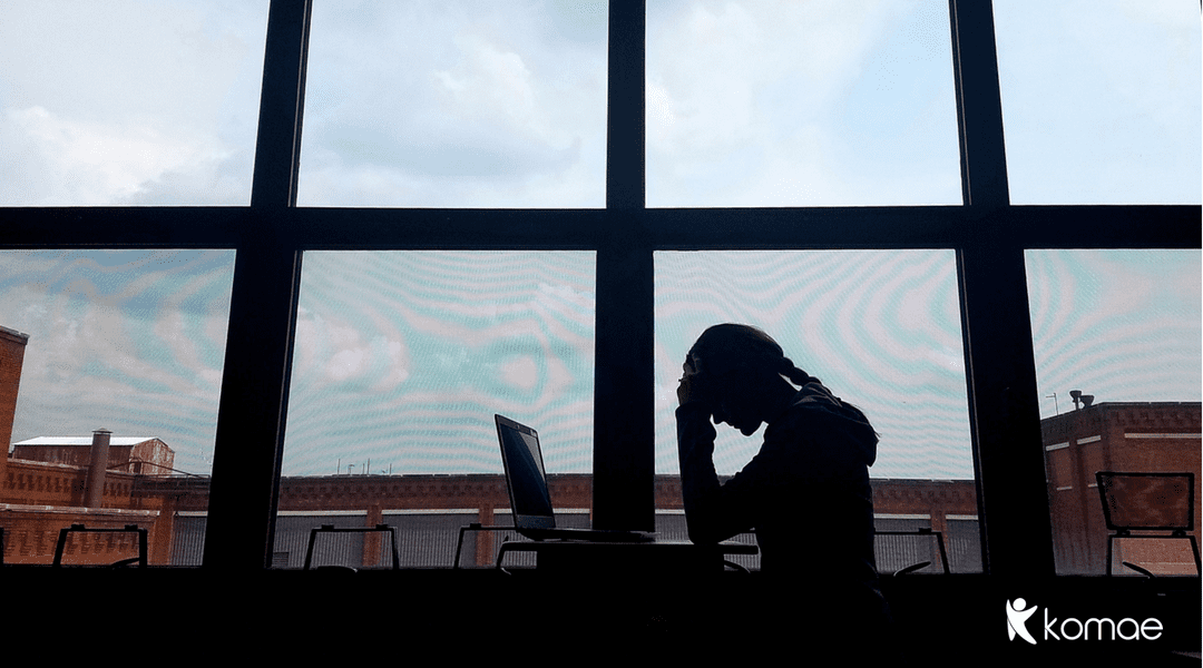 image of a mom sitting by a window with her computer looking stressed out by work
