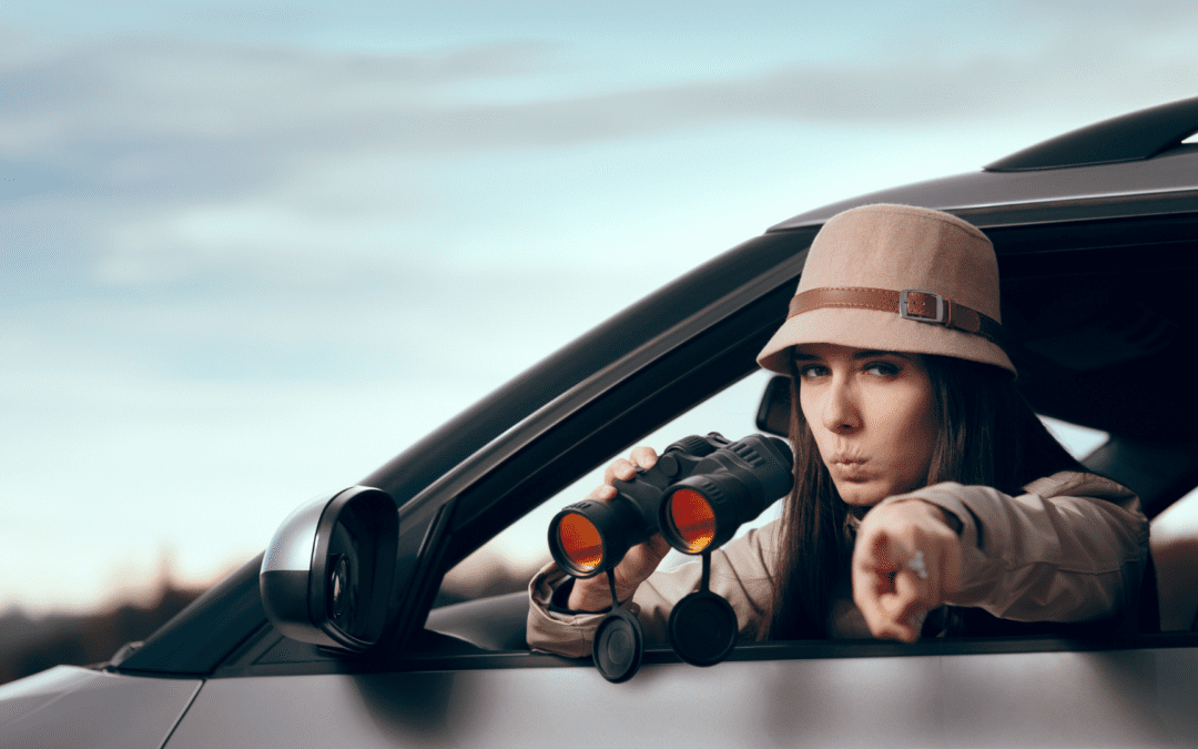 a female in a car with binoculars wearing spy gear