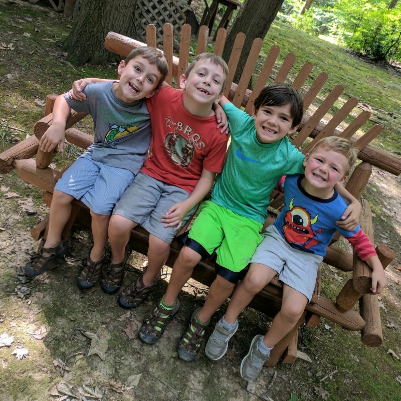 four boys in a park on a bench smiling