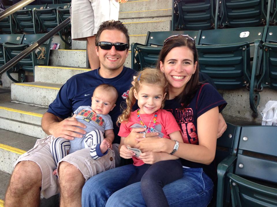 a family with 2 little kids at a baseball game