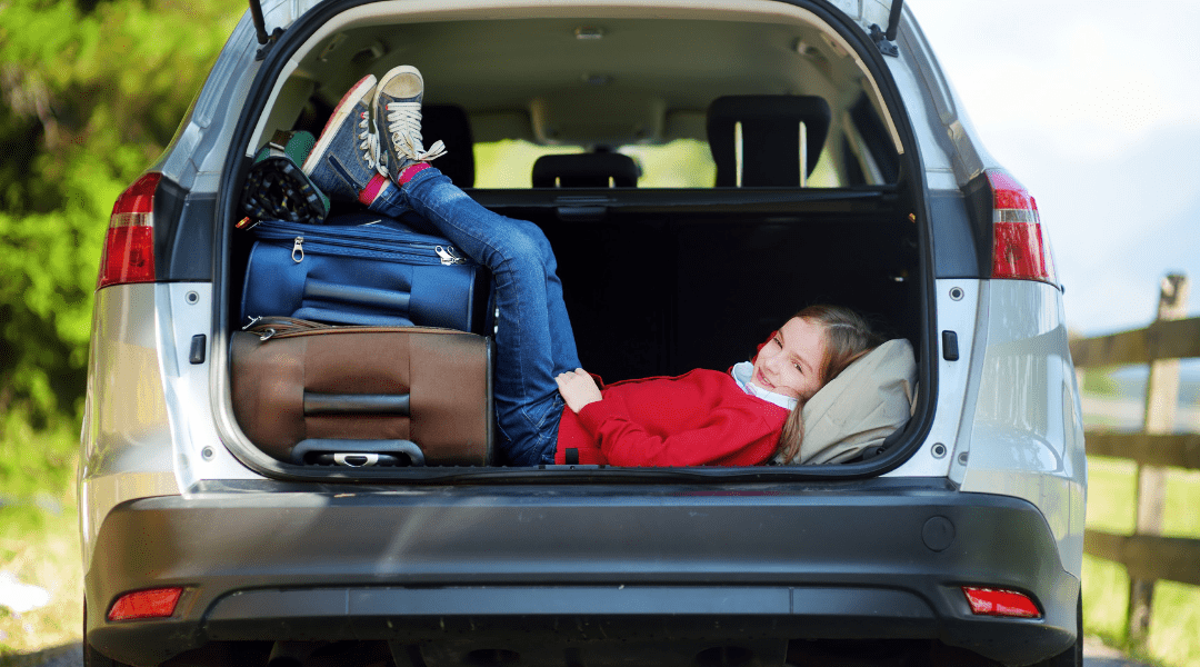 a child wearing red laying in the back of a packed vehicle