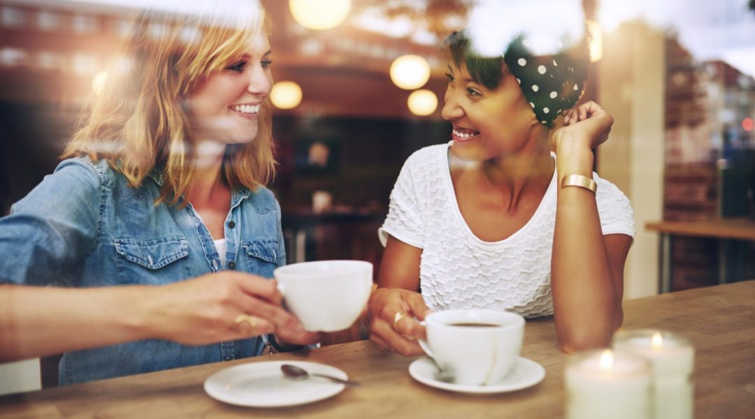 two women sitting in a coffee shop window drinking coffee