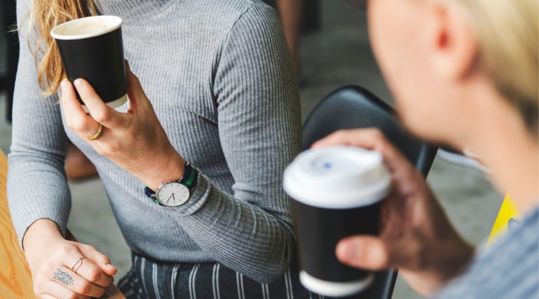 a woman holding up a coffee cup wearing a watch