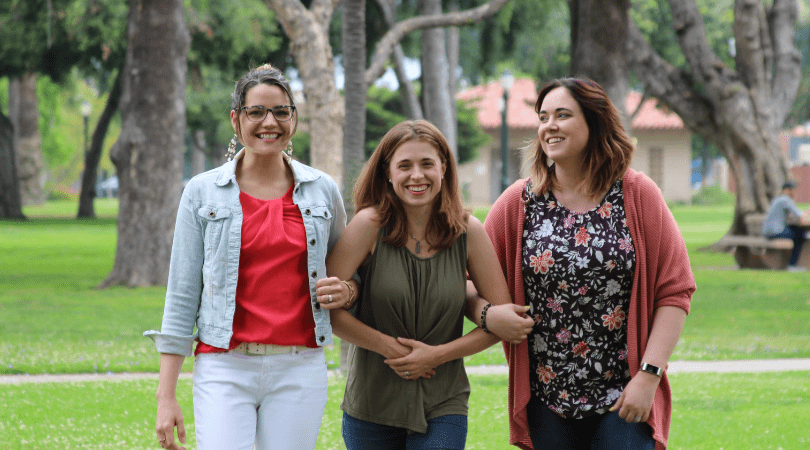 three women holding hands in a park