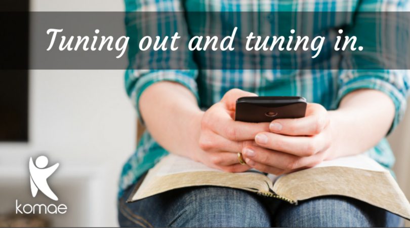 A woman reading her Bible and using her phone. Using apps to connect with your faith.